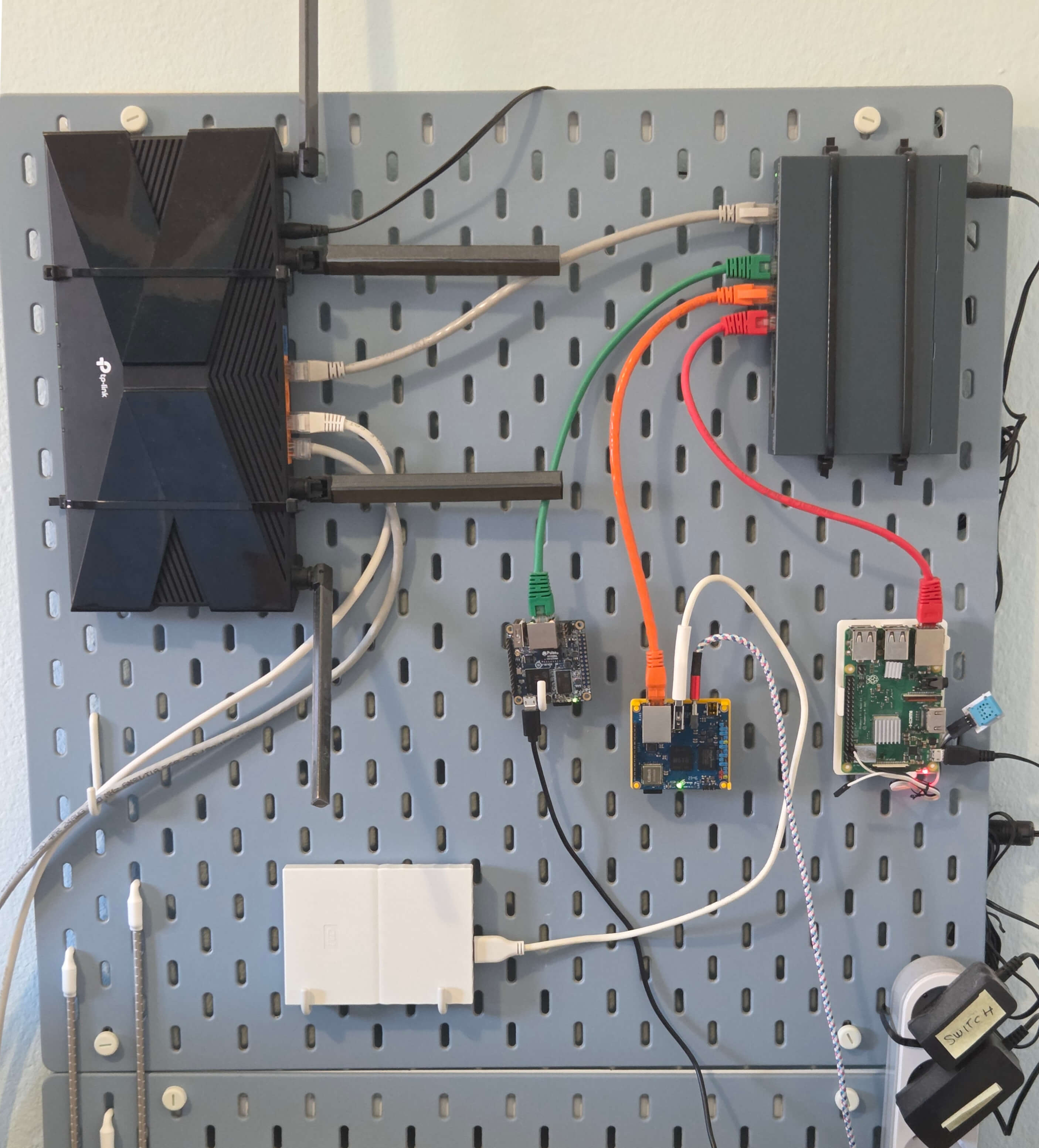 Image showing a wall-mounted homelab with router, switch and a few single-board computers